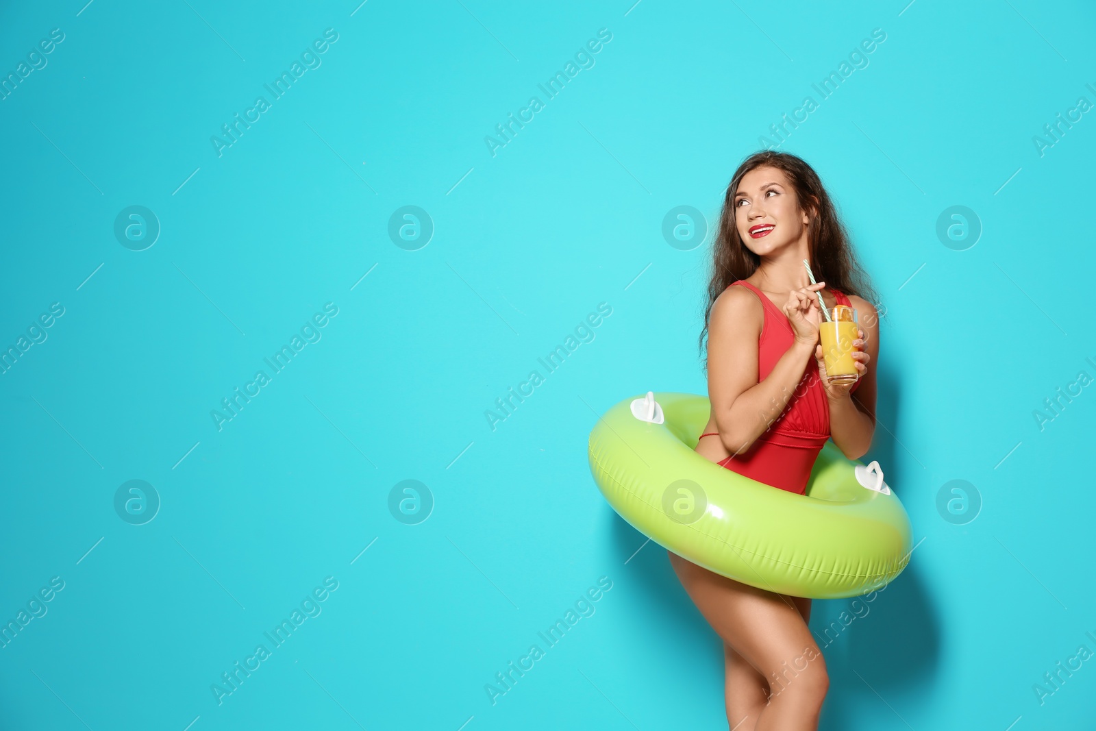 Photo of Beautiful young woman with inflatable ring and glass of cocktail on color background