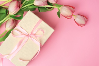 Photo of Beautiful gift box with bow and tulips on pink background, flat lay. Space for text