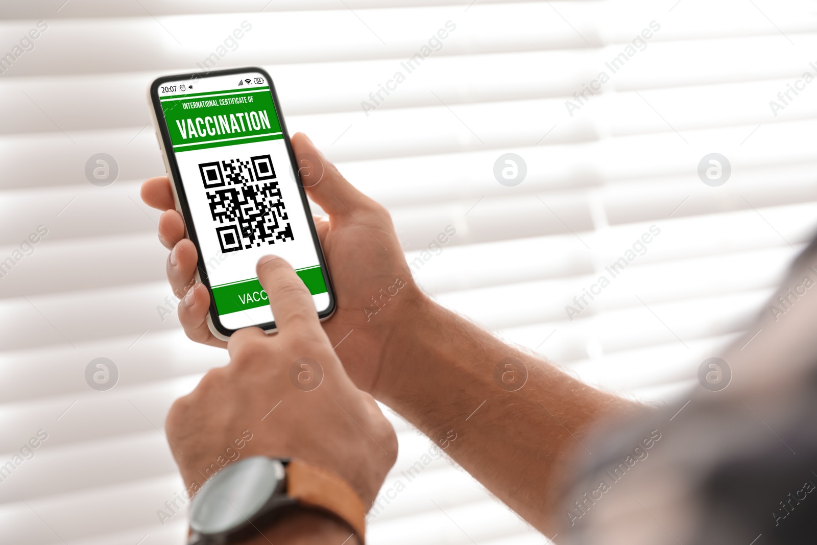 Image of Man holding smartphone with international certificate of vaccination indoors, closeup