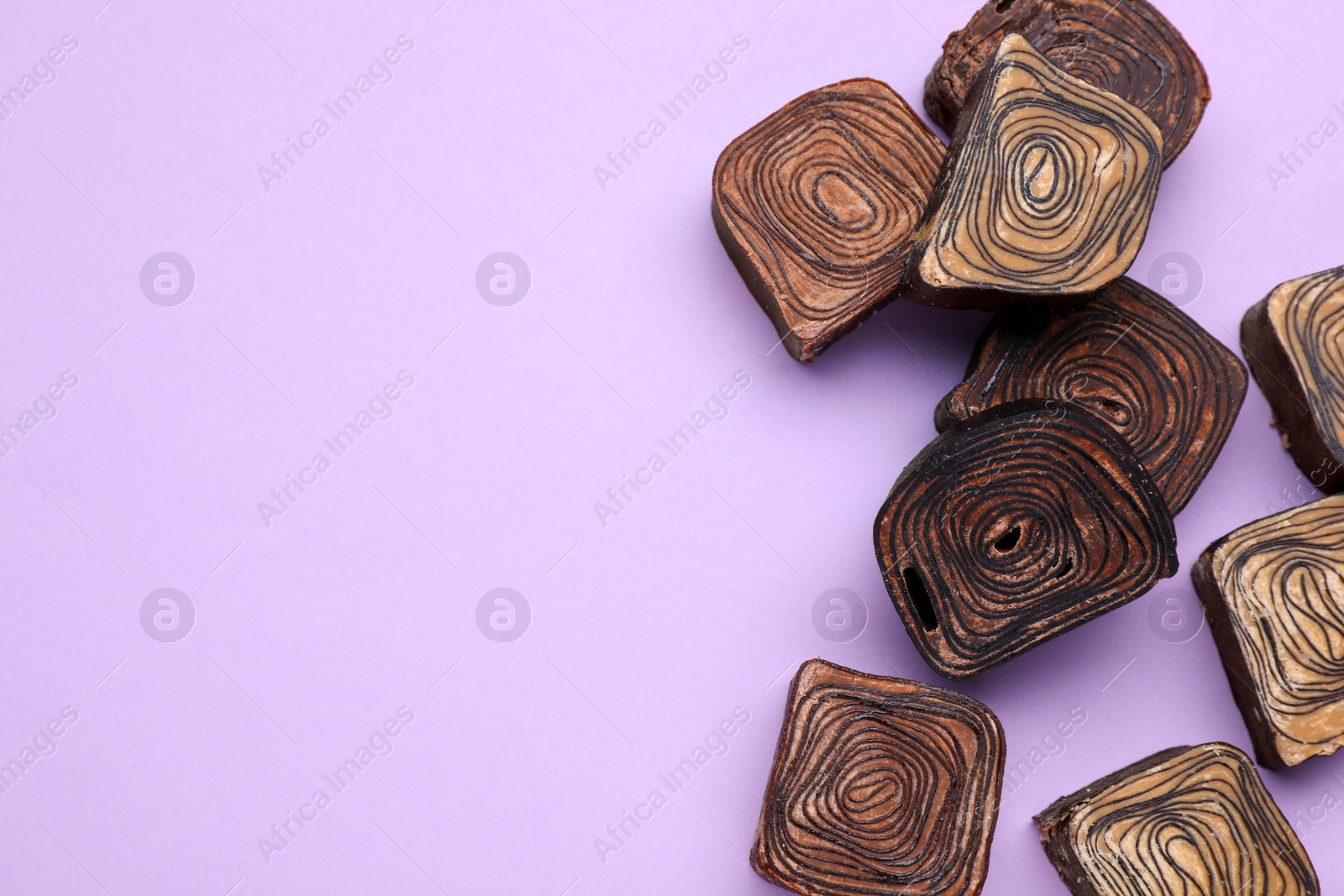 Photo of Tasty chocolate candies on violet background, flat lay. Space for text