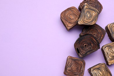 Photo of Tasty chocolate candies on violet background, flat lay. Space for text