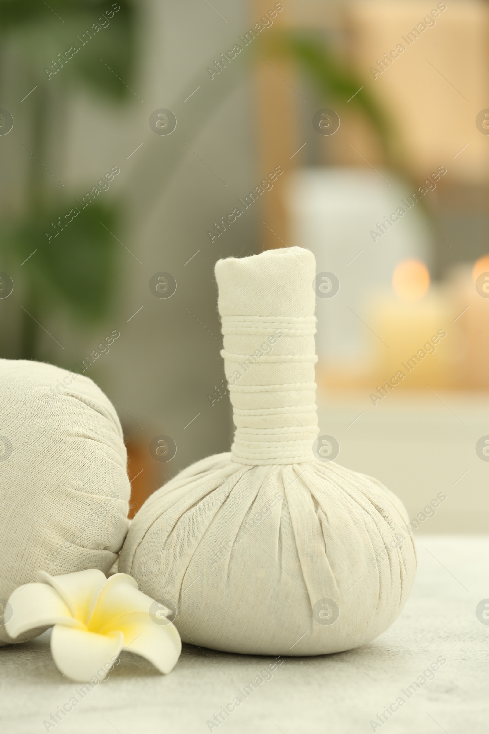 Photo of Beautiful spa composition with herbal massage bags and plumeria flower on light grey table in wellness center