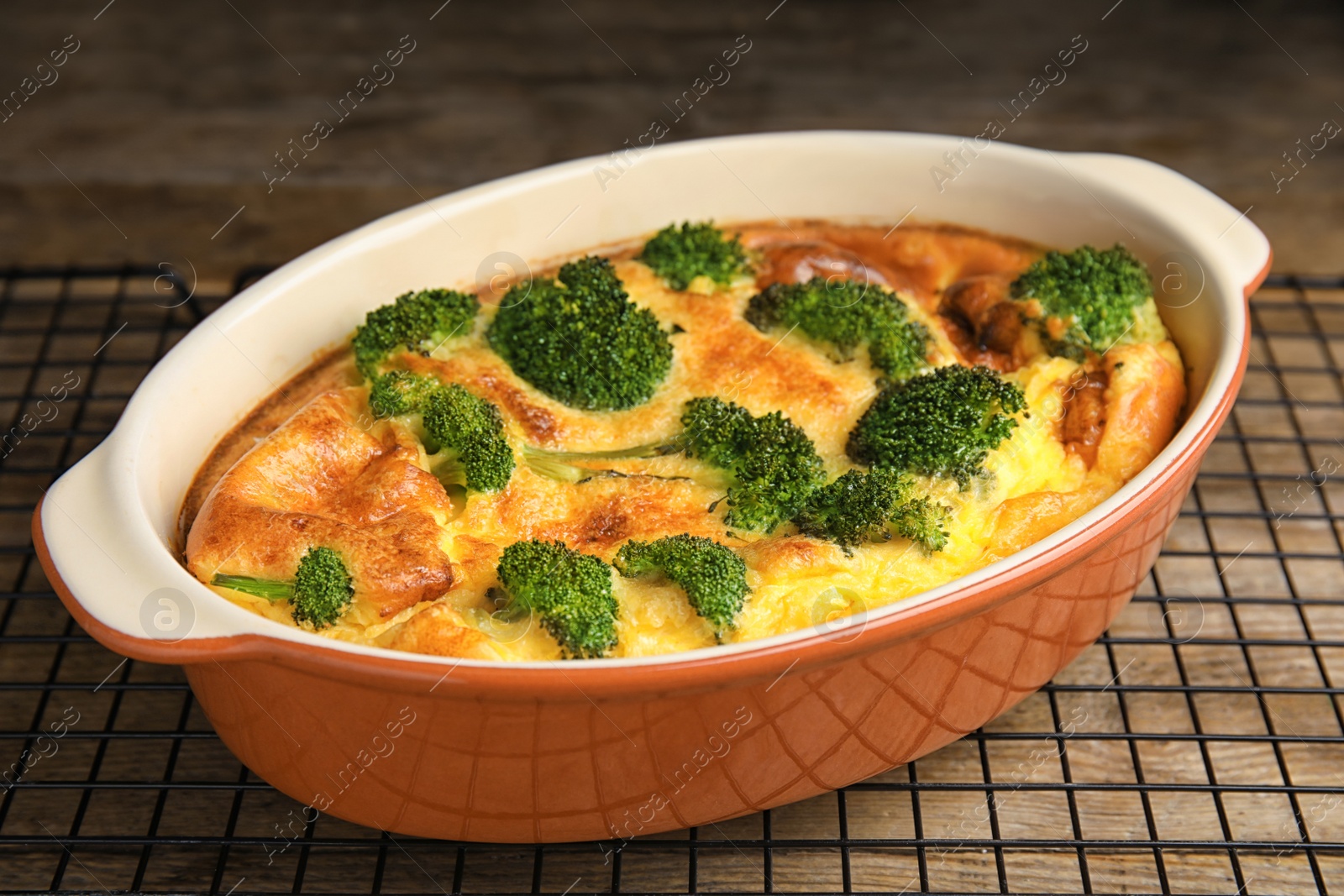 Photo of Tasty broccoli casserole in baking dish on cooling rack