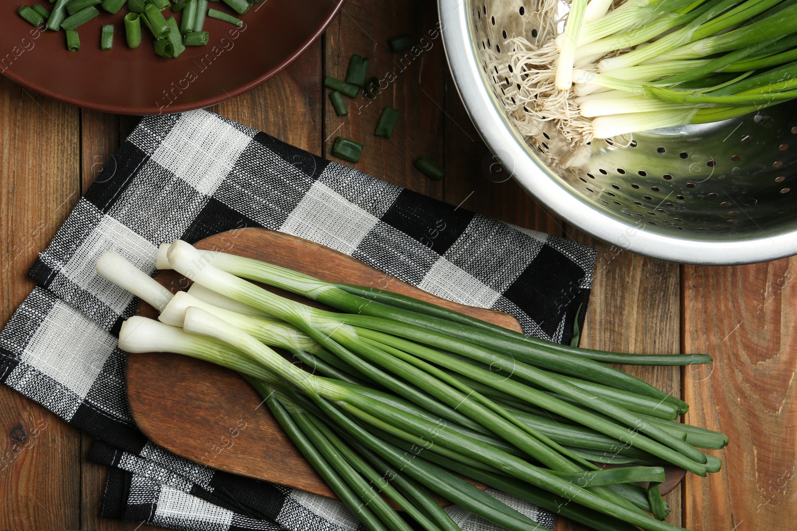 Photo of Fresh green spring onions on wooden table, flat lay