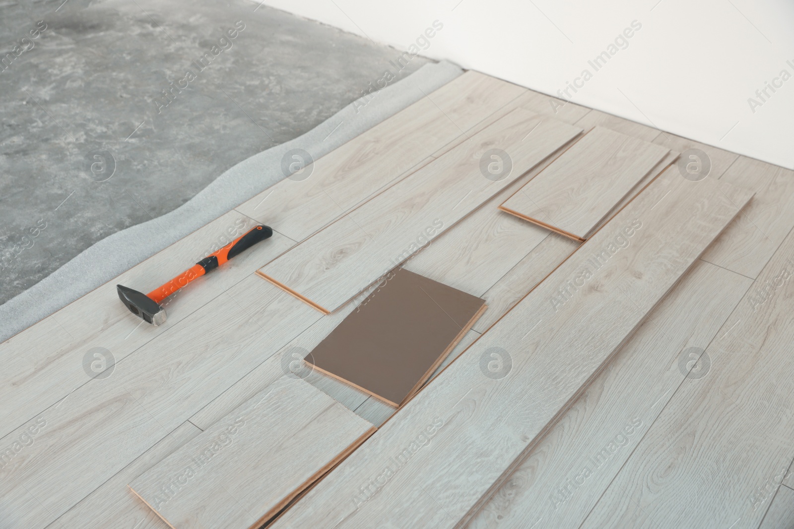 Photo of Parquet planks and hammer on floor in room prepared for renovation