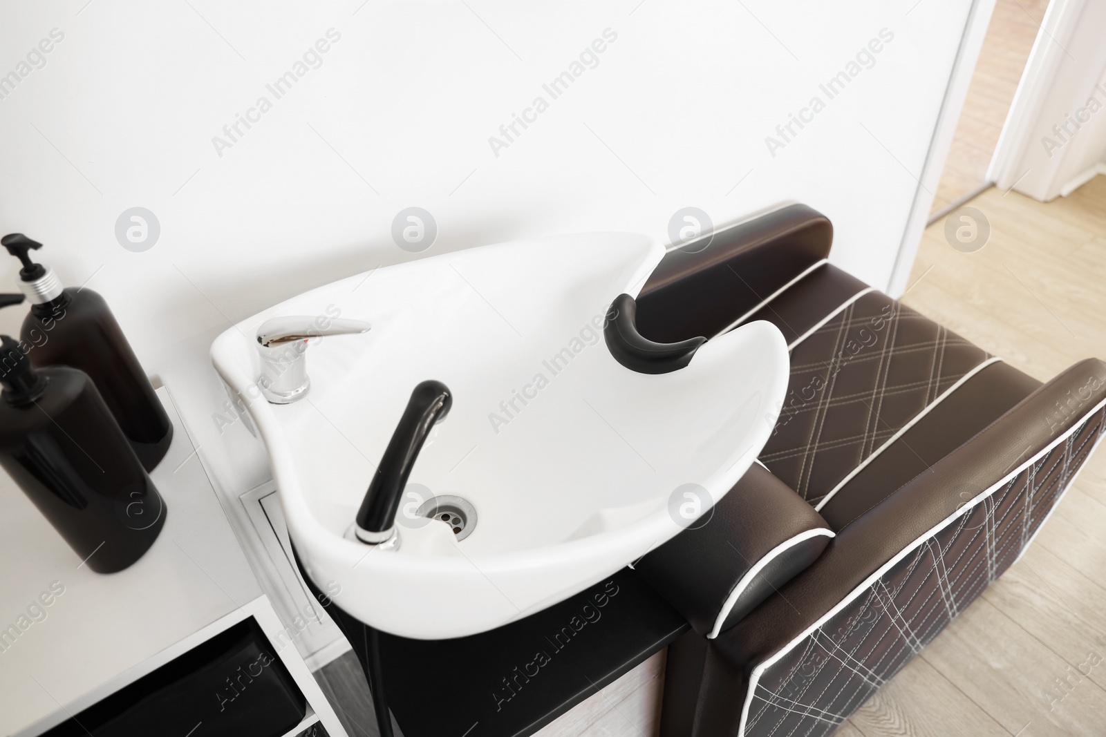 Photo of Modern wash unit with professional care products in barbershop, above view