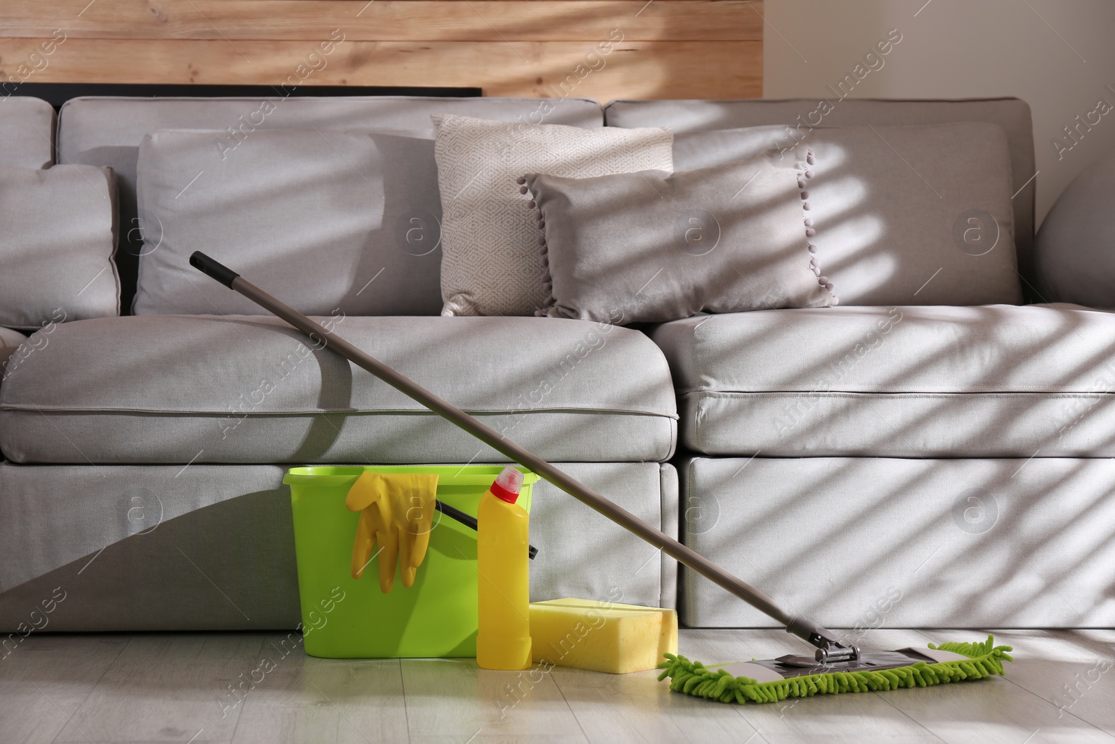 Photo of Floor mop, cleaning detergent, sponge and bucket with gloves in living room