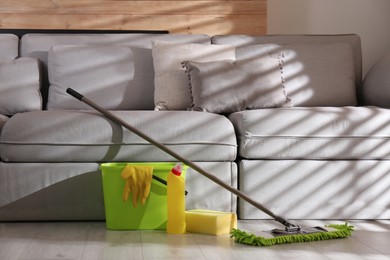 Floor mop, cleaning detergent, sponge and bucket with gloves in living room