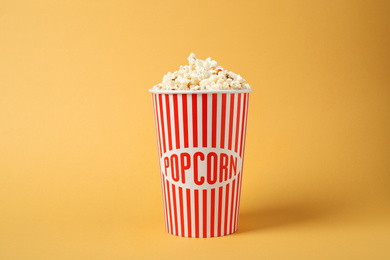 Photo of Delicious popcorn in paper cup on yellow background