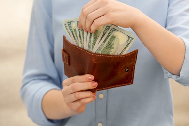 Photo of Woman counting dollar bills on beige background, closeup. Money exchange