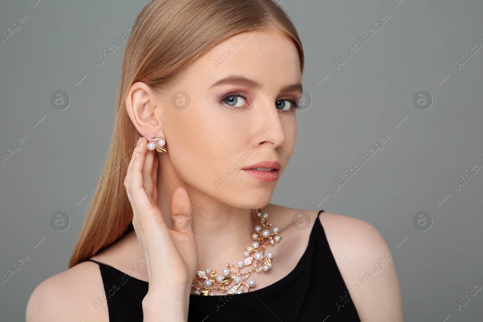 Photo of Beautiful young woman with elegant jewelry on gray background