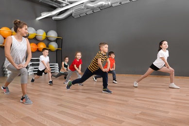 Photo of Cute little children and trainer doing physical exercise in school gym. Healthy lifestyle