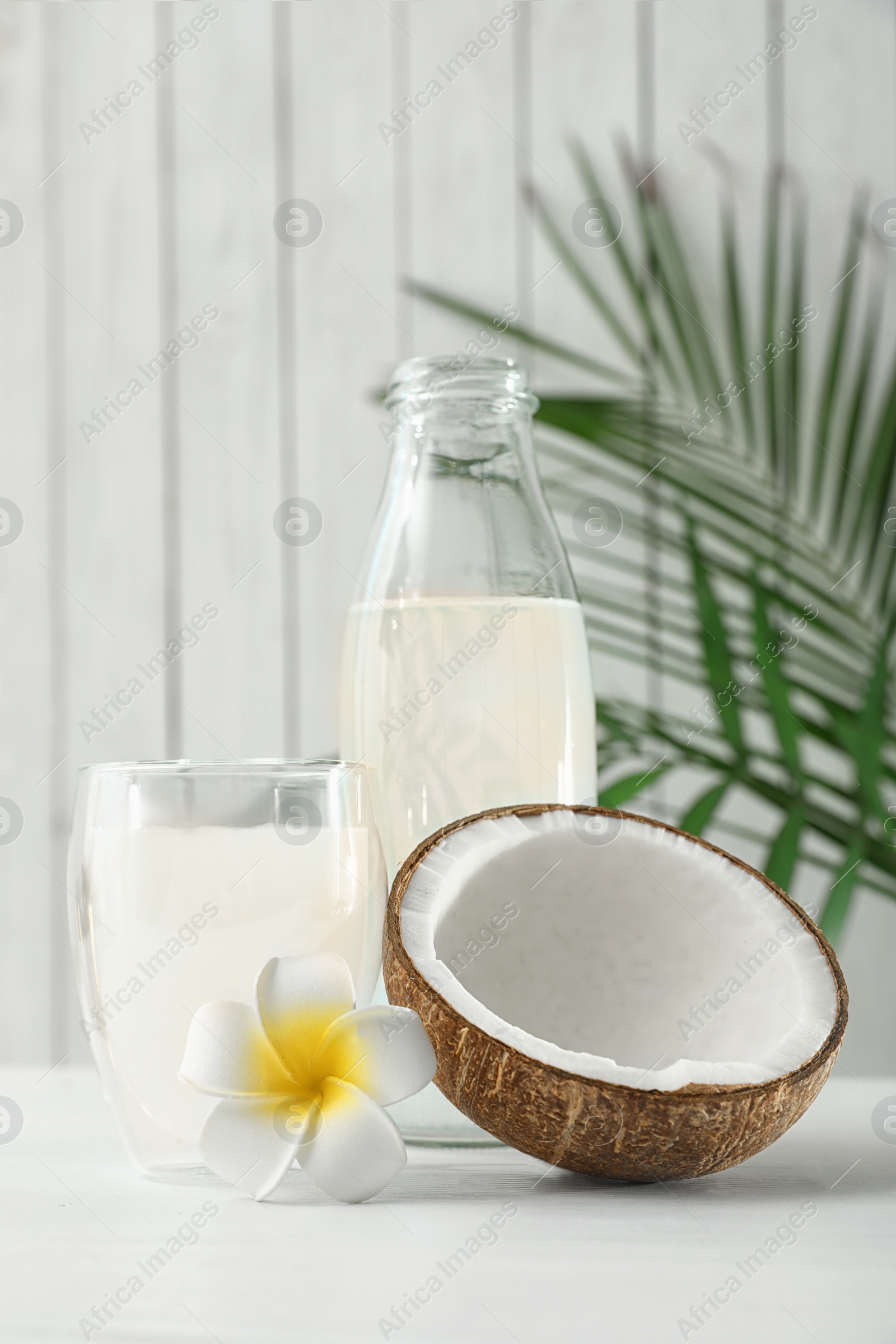 Photo of Composition with bottle and glass of coconut water on white wooden table
