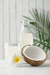 Composition with bottle and glass of coconut water on white wooden table