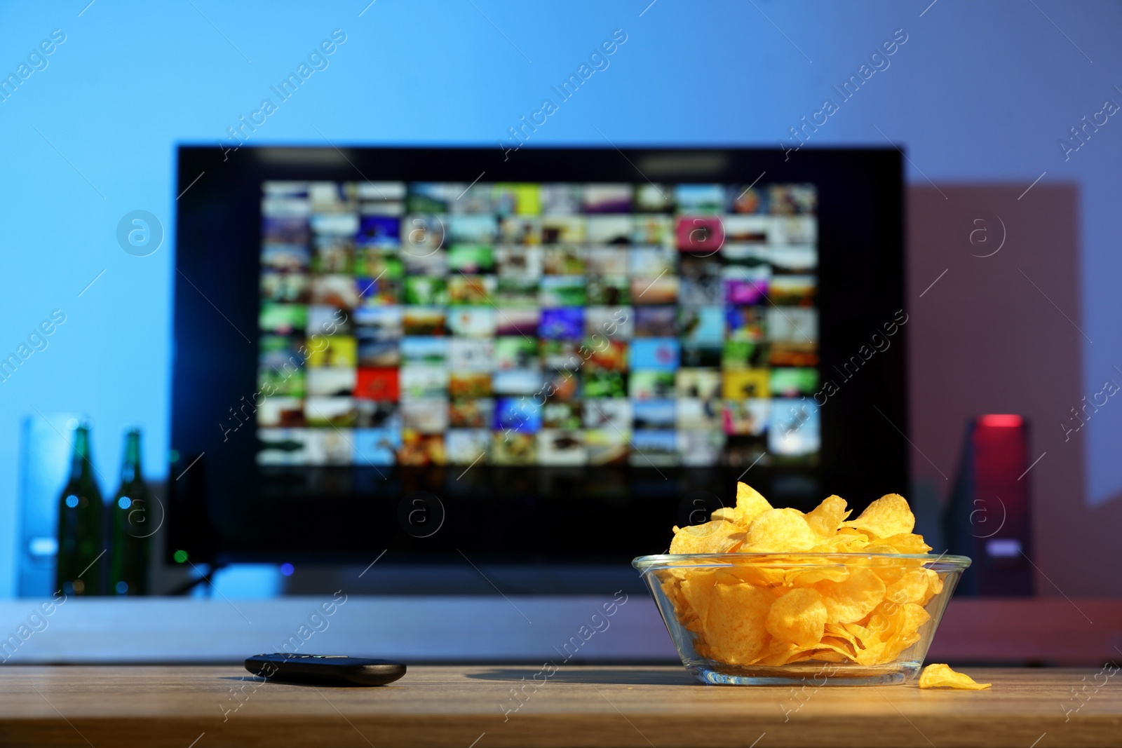 Photo of Bowl of chips and TV remote control on table indoors. Space for text