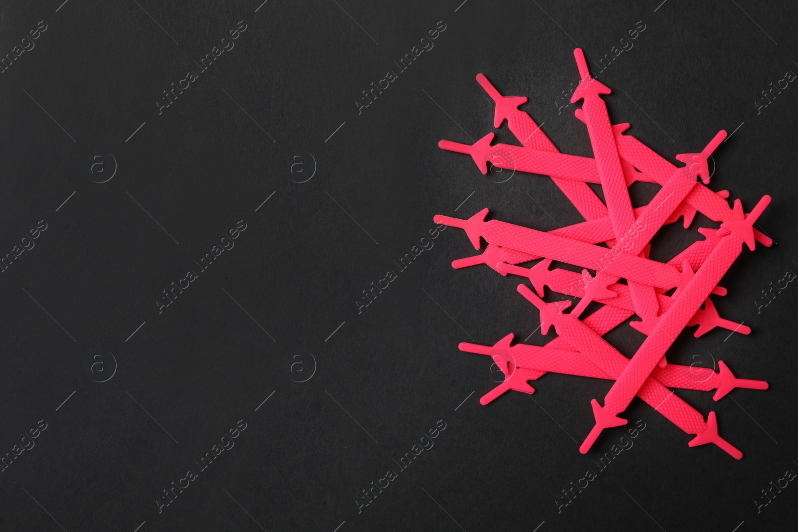 Photo of Pink silicone shoelaces on black background, flat lay. Space for text