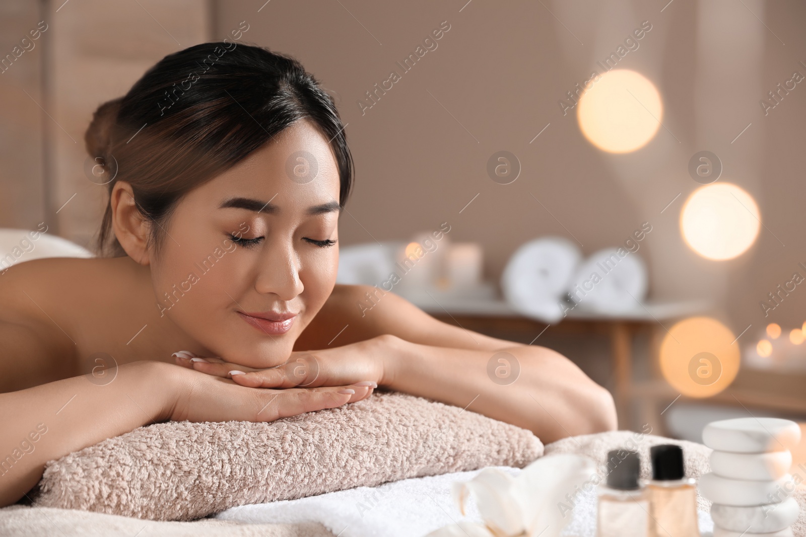 Photo of Beautiful Asian woman lying on massage table in spa salon. Space for text