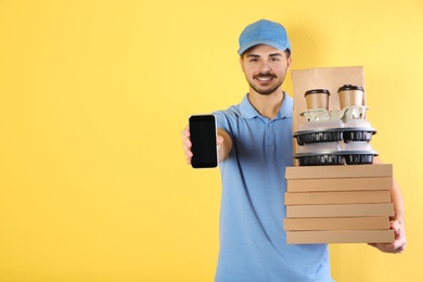 Young man holding orders and smartphone on color background, mockup for design. Online food delivery