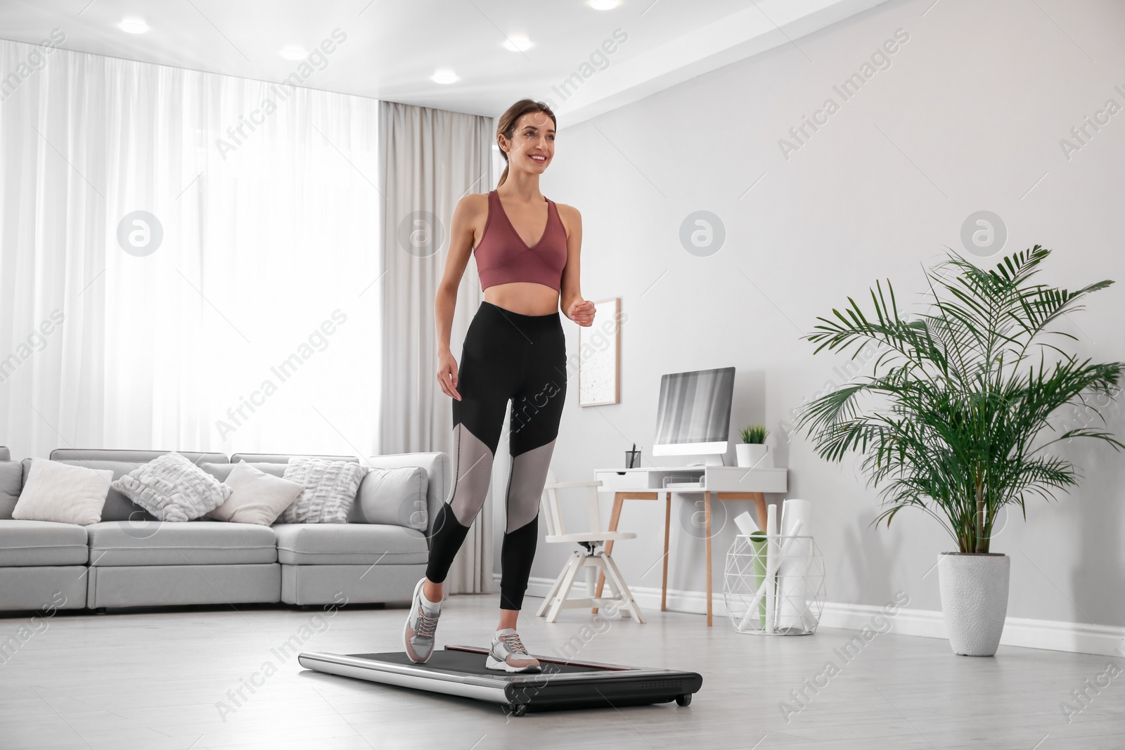 Photo of Sporty woman training on walking treadmill at home