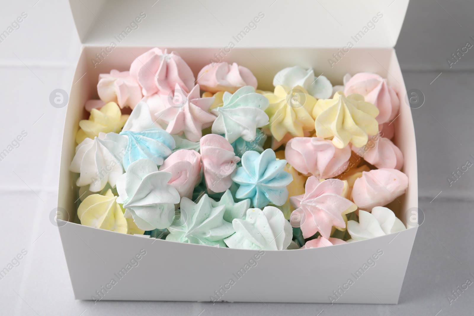 Photo of Tasty meringue cookies on white tiled table