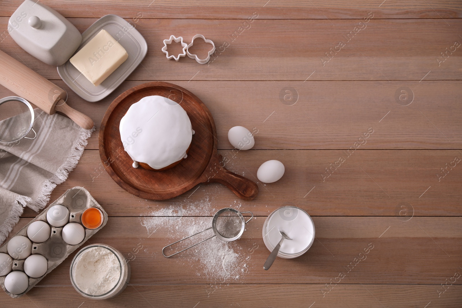 Photo of Flat lay composition with traditional Easter cake and ingredients on wooden table, space for text