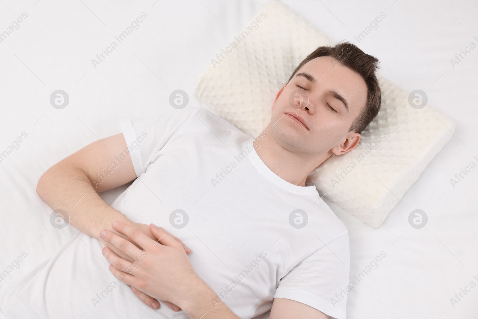 Photo of Man sleeping on orthopedic pillow in bed