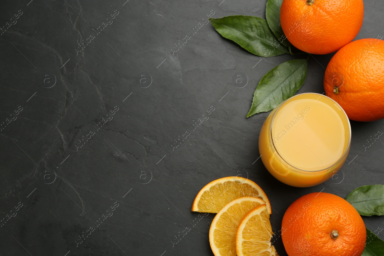 Photo of Delicious orange juice and fresh fruits on black table, flat lay. Space for text