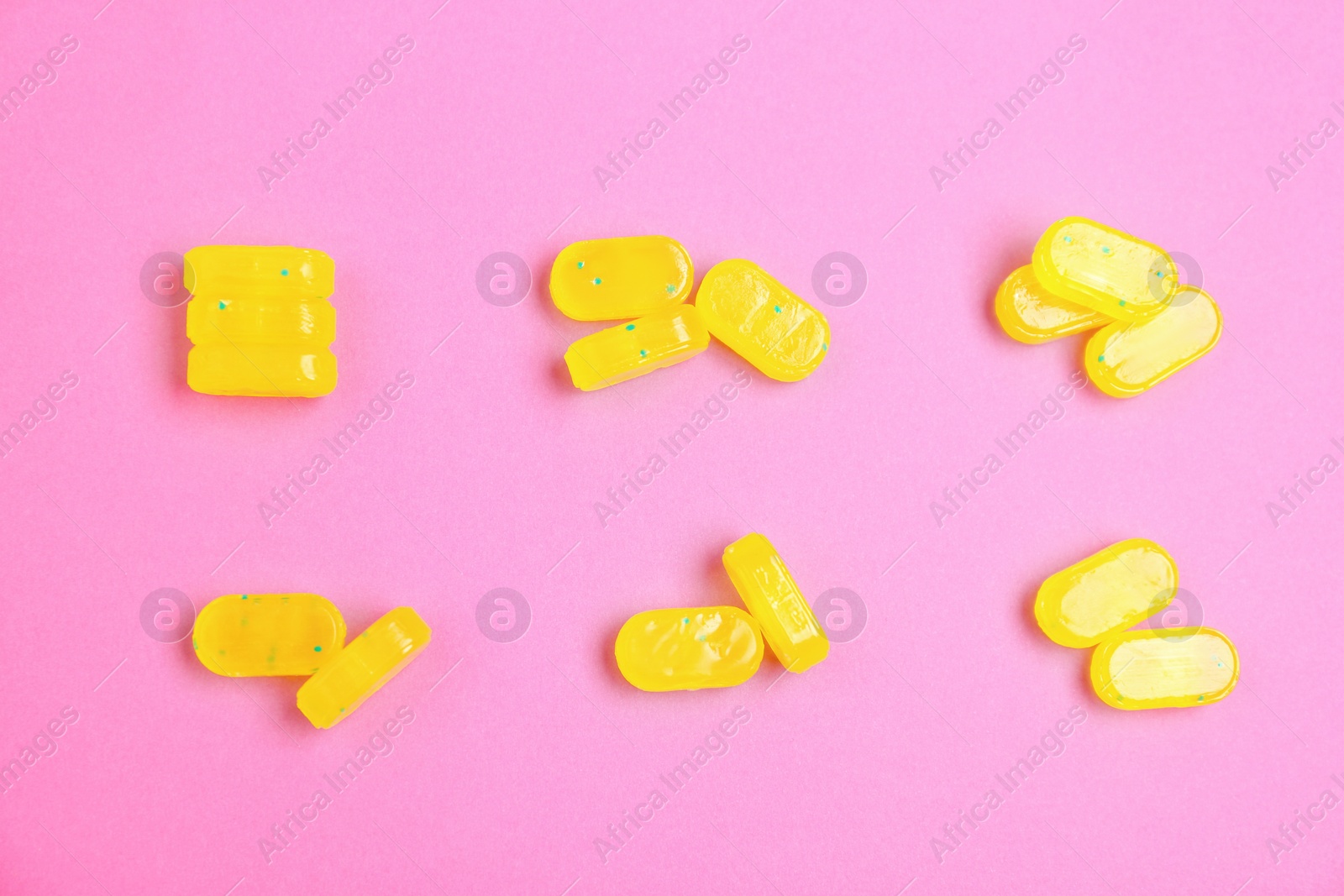 Photo of Tasty lemon drops on pink background, flat lay