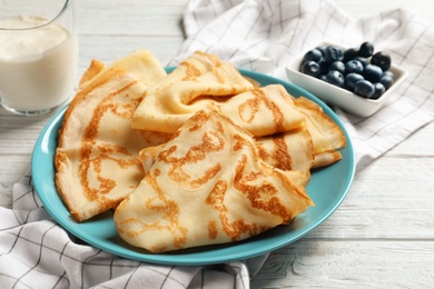 Plate with thin pancakes on table