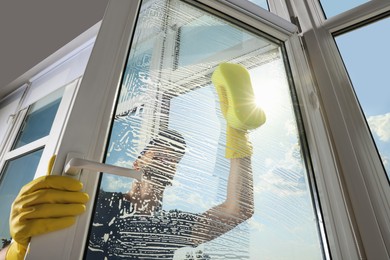 Photo of Man cleaning glass with sponge indoors, low angle view