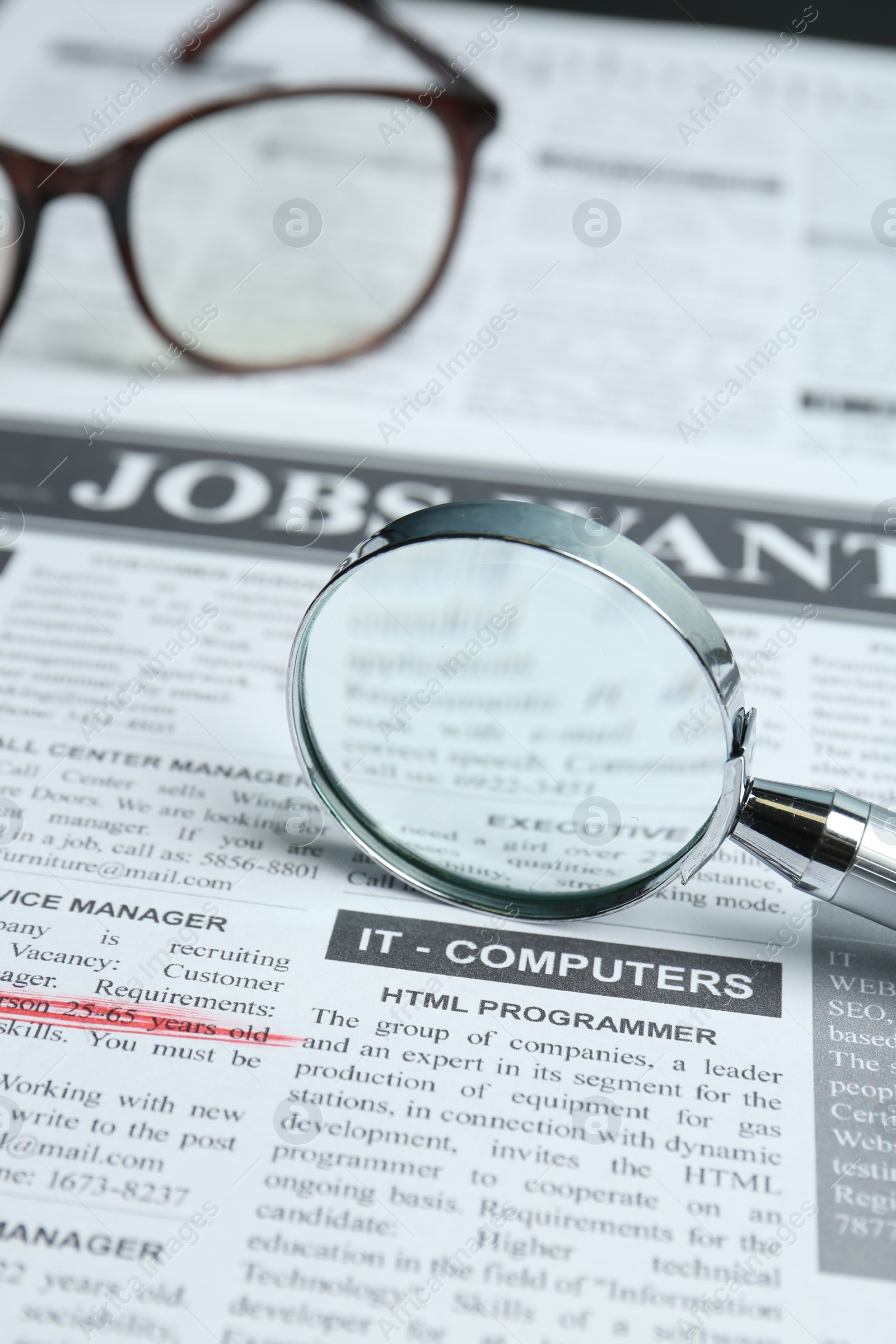 Photo of Magnifier and glasses on newspaper. Job search concept