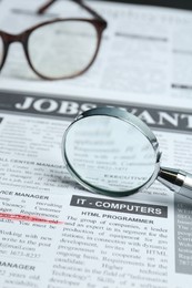 Photo of Magnifier and glasses on newspaper. Job search concept