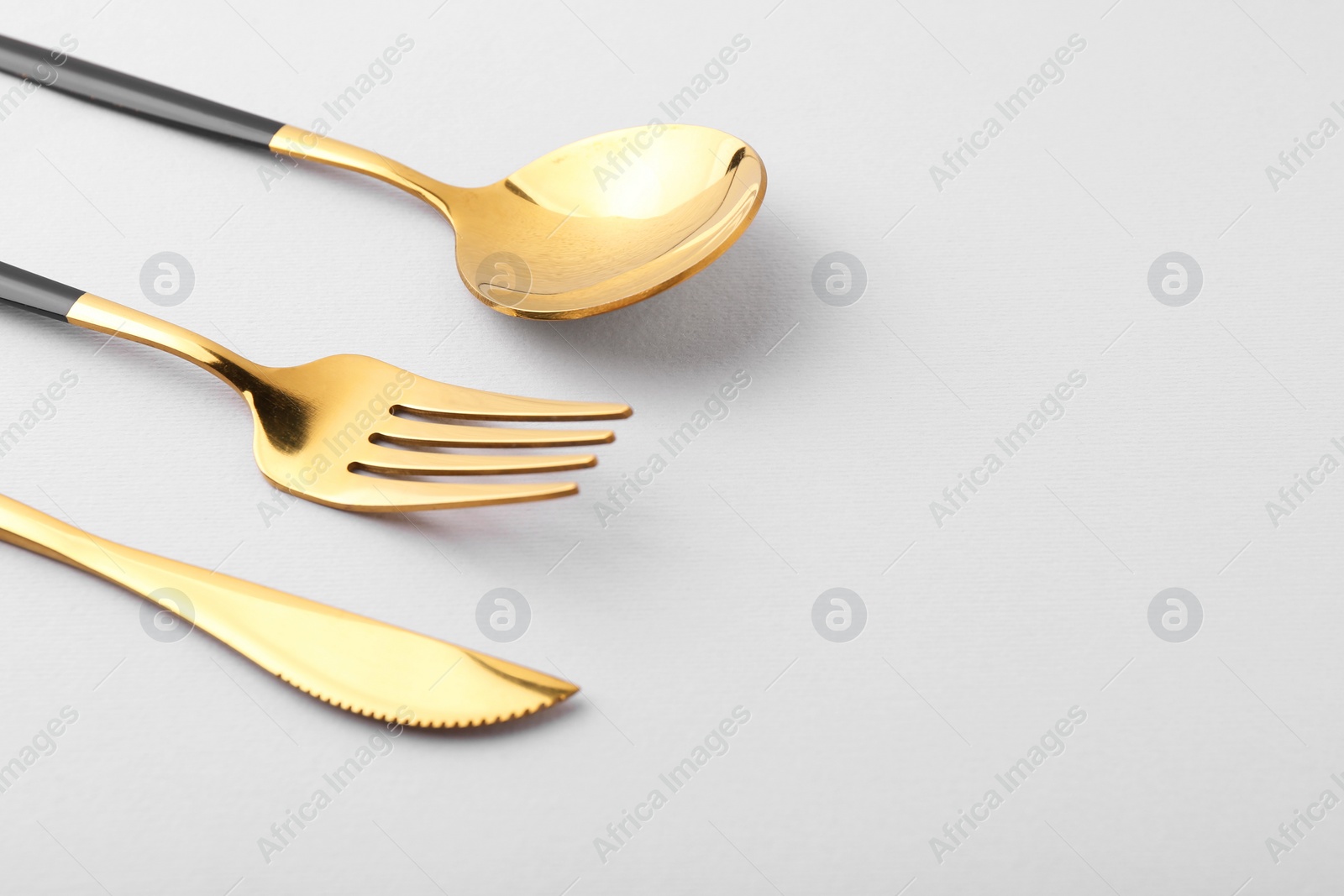 Photo of Stylish golden cutlery set on gray background, closeup. Space for text
