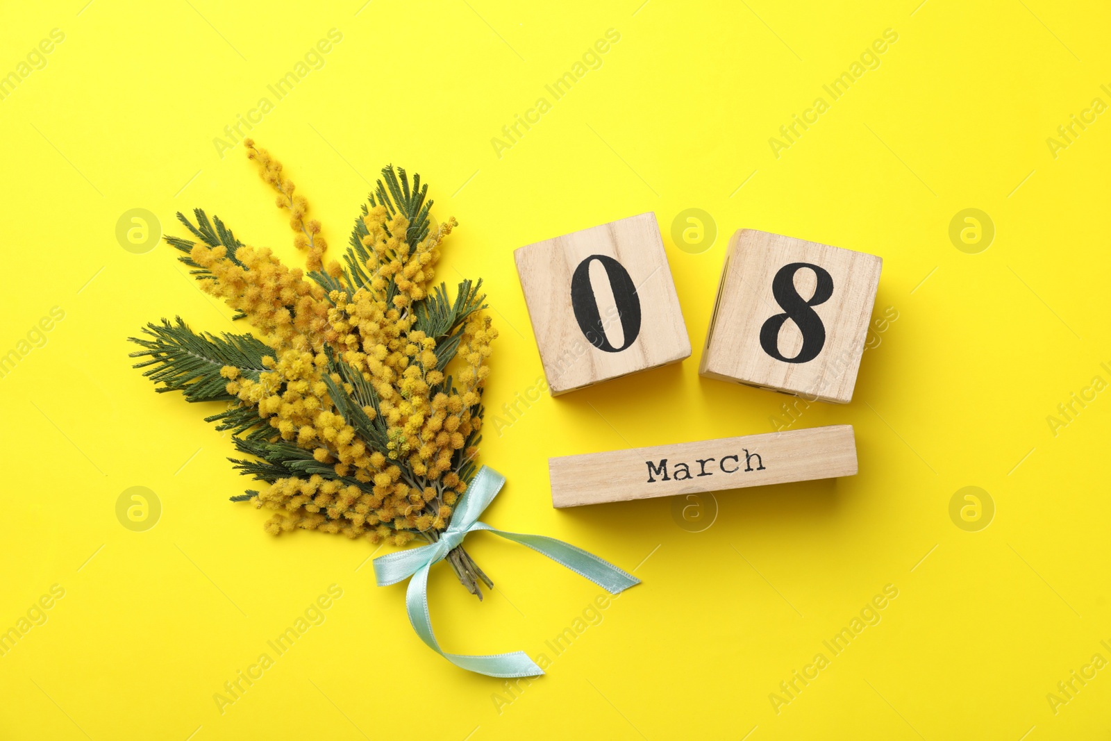 Photo of 8 March greeting card design with beautiful mimosa flowers on yellow background, flat lay