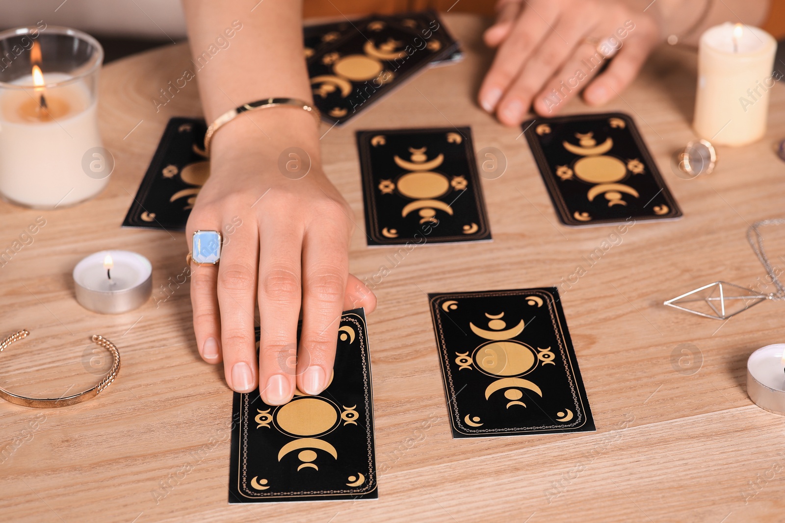 Photo of Soothsayer predicting future with tarot cards at wooden table, closeup