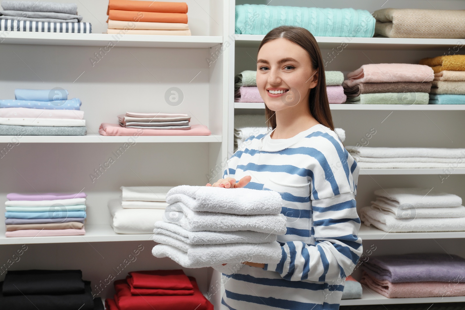 Photo of Happy customer holding stack of towels in linen shop, space for text