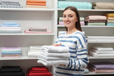 Photo of Happy customer holding stack of towels in linen shop, space for text