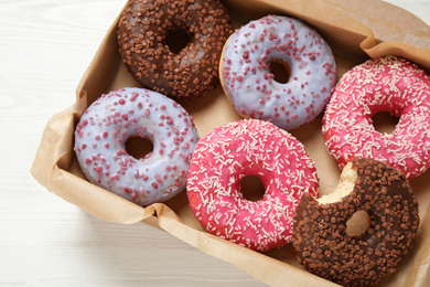 Delicious glazed donuts on white wooden table, top view