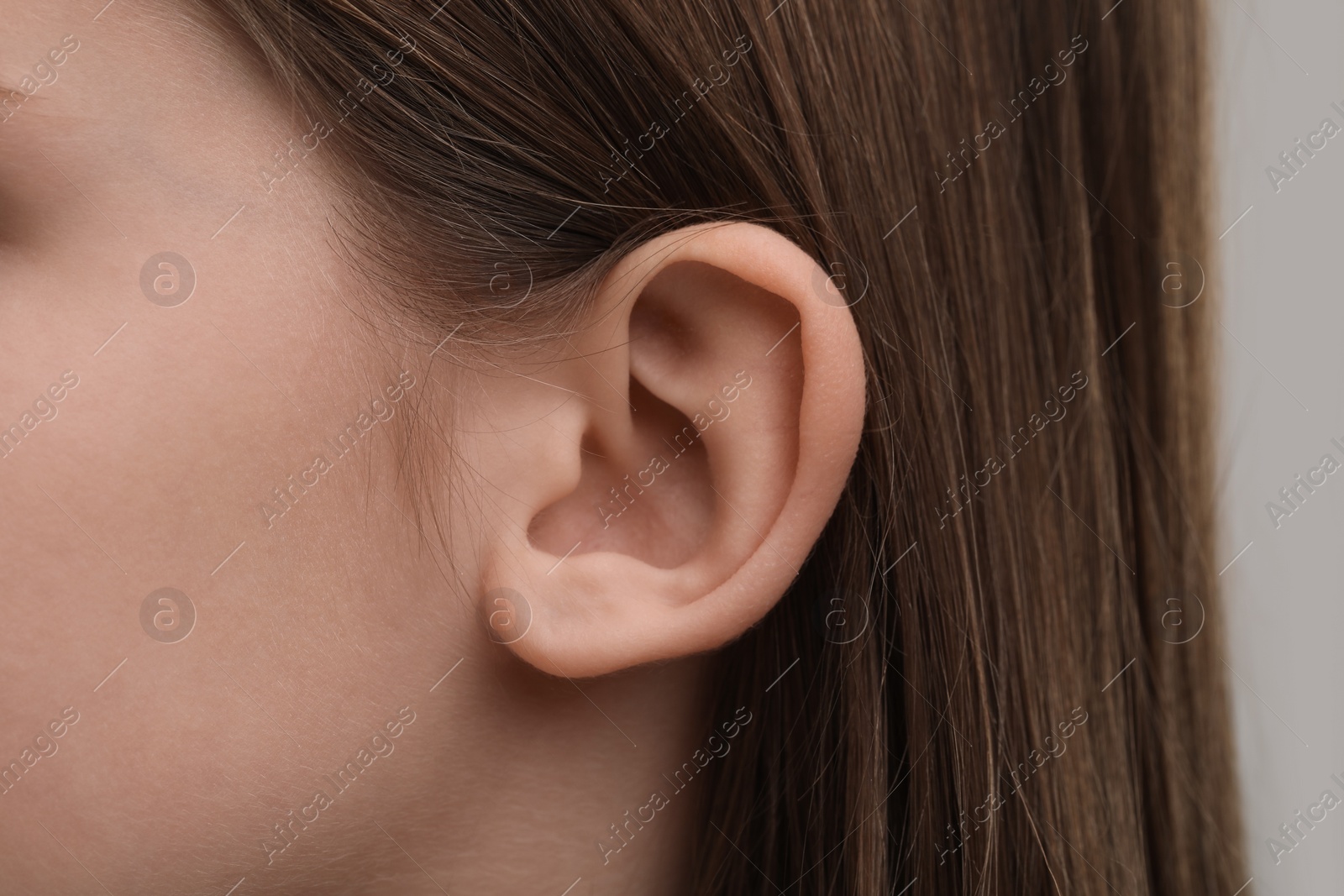 Photo of Hearing problem. Little girl on grey background, closeup