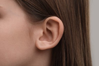 Photo of Hearing problem. Little girl on grey background, closeup