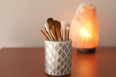 Holder with makeup brushes on table