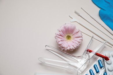 Gynecological tools, pills and gerbera flower on beige background, flat lay. Space for text