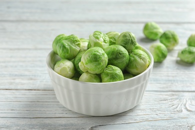 Photo of Bowl of fresh Brussels sprouts on wooden table