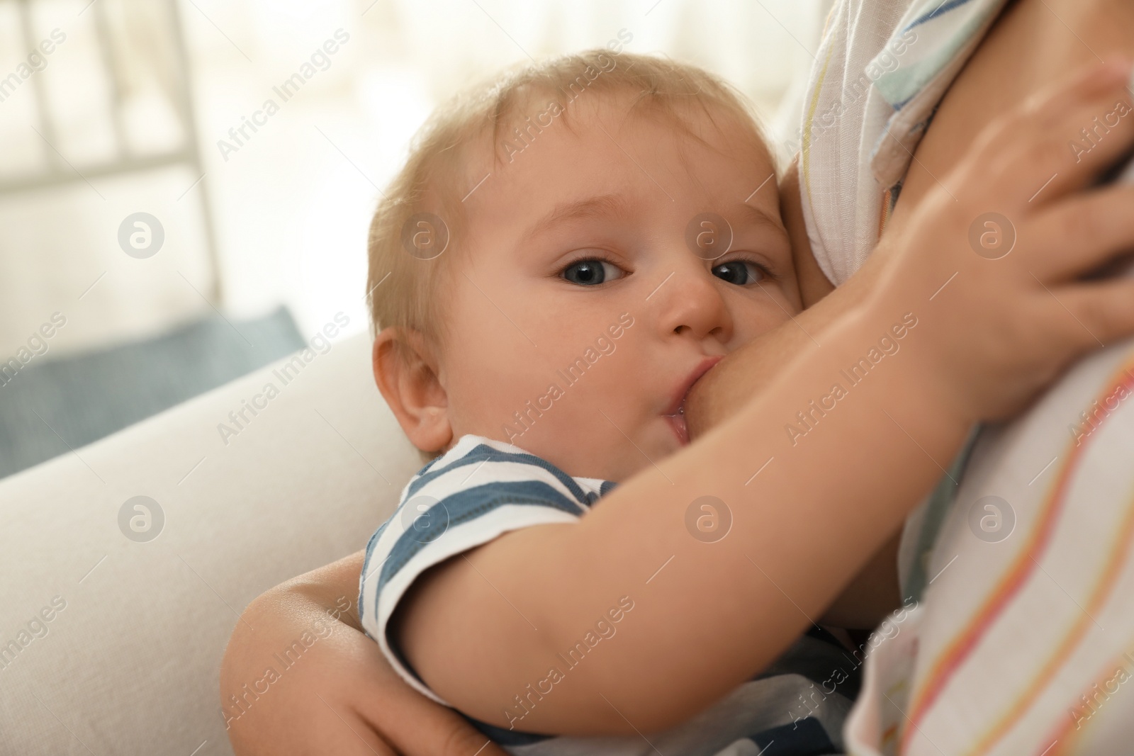 Photo of Woman breastfeeding her little baby at home, closeup