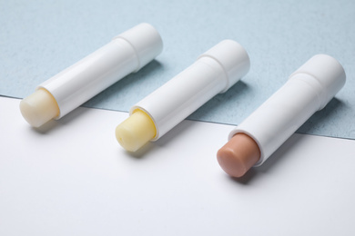 Photo of Different hygienic lipsticks on color background, closeup