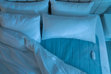 Photo of Bed with electric heating pad indoors at night