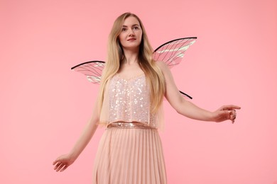 Beautiful girl in fairy costume with wings on pink background