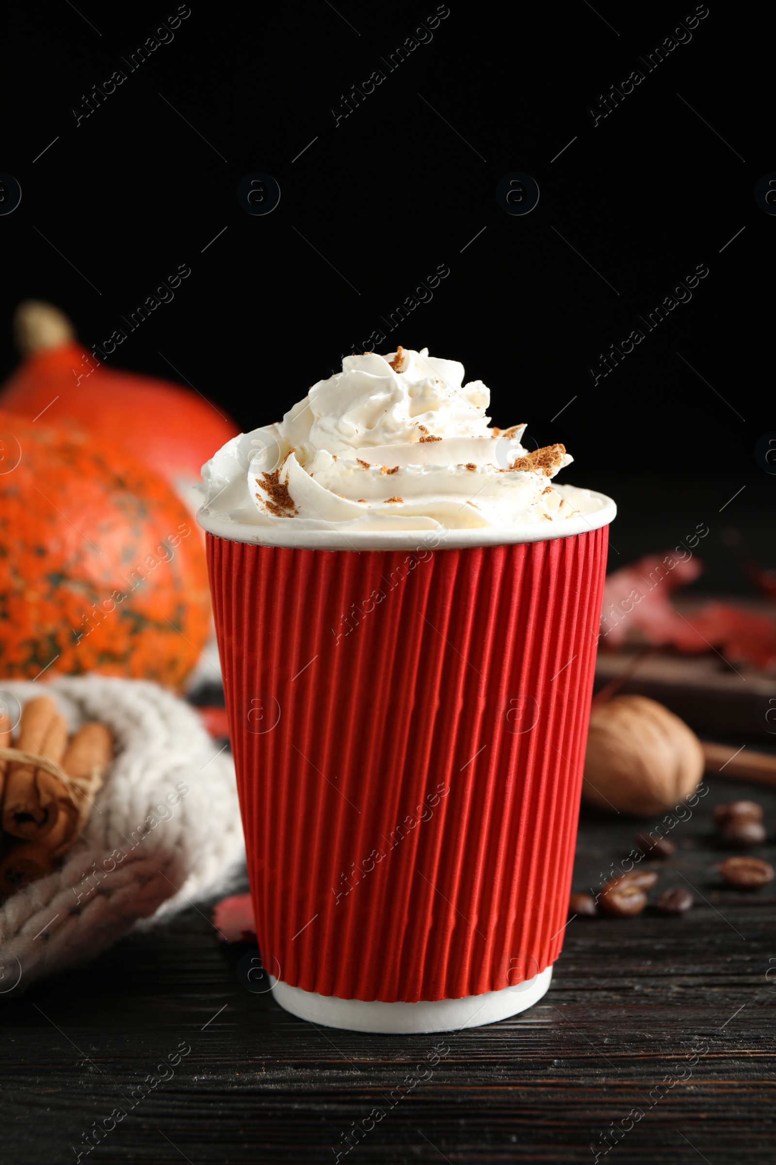 Photo of Paper cup with tasty pumpkin spice latte on black wooden table
