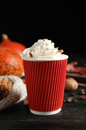 Paper cup with tasty pumpkin spice latte on black wooden table