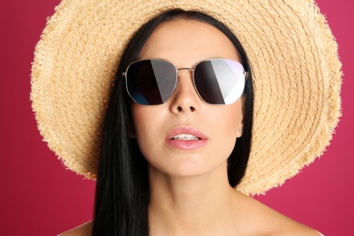 Beautiful woman wearing sunglasses on pink background, closeup